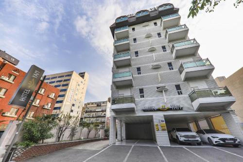 a tall building with cars parked in front of it at Hotel Yeosu Yam Hakdong in Yeosu