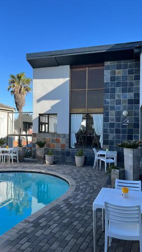 um pátio com uma mesa e cadeiras ao lado de uma piscina em Le Blue Guesthouse em Port Elizabeth