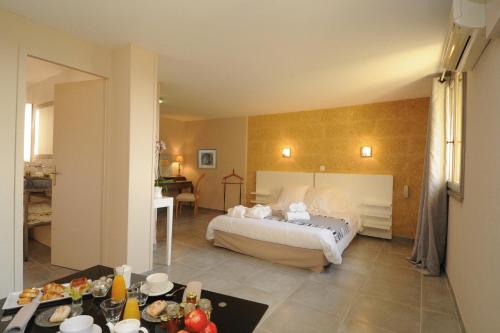 a hotel room with a bed and a dining room at Le Mas Des Aigras - Hôtel de Charme en Provence in Orange