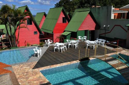 a pool with tables and chairs next to some buildings at Pousada Chale Pico da Bandeira in Alto Caparao