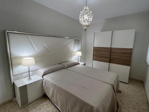 um quarto com uma cama grande e um lustre em APARTAMENTO AREVALO LUCENA CENTER em Lucena