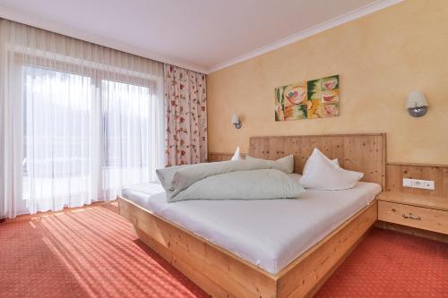 um quarto com uma cama grande e uma janela em Pension Grünerhof em Sölden