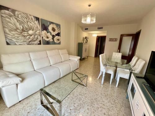 uma sala de estar com um sofá branco e uma mesa de vidro em APARTAMENTO AREVALO LUCENA CENTER em Lucena