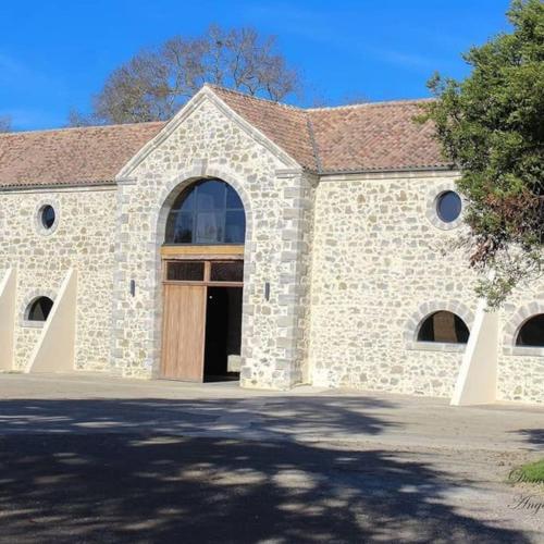 - un bâtiment en pierre avec une grande porte et un arbre dans l'établissement Cottage chaleureux dans un Domaine d'exception, à Nomdieu