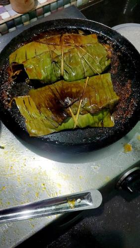 a pan with a piece of food sitting on a stove with a knife at Kudil Mud Cottages, Cheemeni in Peringom
