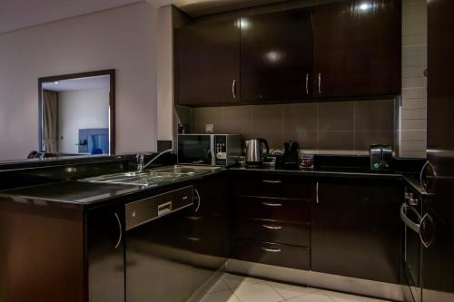 a kitchen with black cabinets and a sink and a microwave at Relaxing 1 bedroom apartment at 5 Star Resort in Dubai