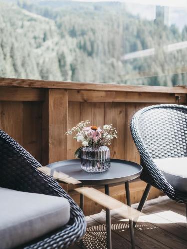 a table with two chairs and a vase of flowers on a balcony at VAYA Gerlos in Gerlos