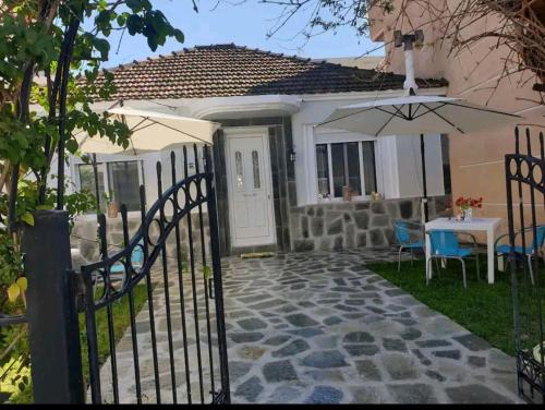 um portão para uma casa com uma mesa e um guarda-chuva em Dimitri's house em Néa Péramos