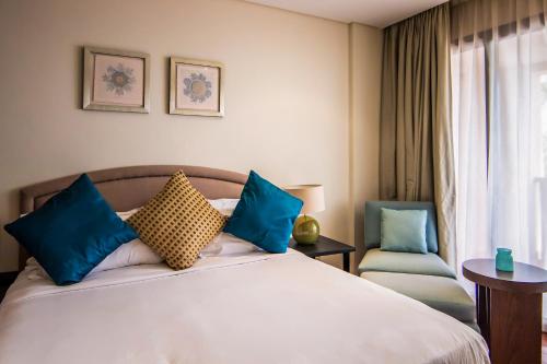 a bedroom with a bed with blue pillows and a chair at Relaxing 1 bedroom apartment at 5 Star Resort in Dubai
