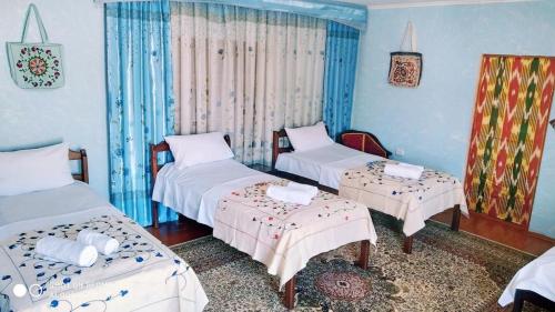 Habitación con 3 camas y 2 mesas. en Ali Nur en Bukhara