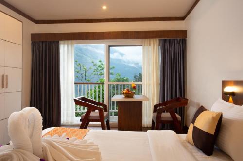 a bedroom with a bed and a window and a table at Dream Catcher Plantation Resort in Munnar