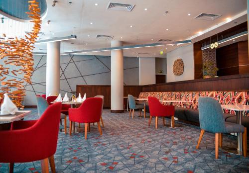 a restaurant with red and blue chairs and tables at Crowne Plaza - Dar Es Salaam by IHG in Dar es Salaam