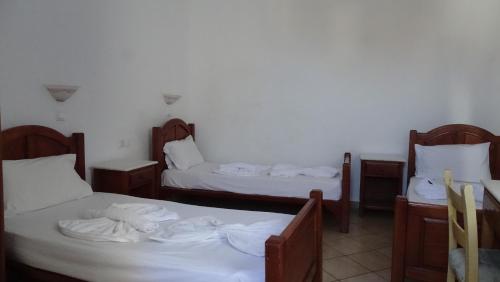 a room with two beds with white sheets at Hermes-Ios Rooms To Let in Ios Chora