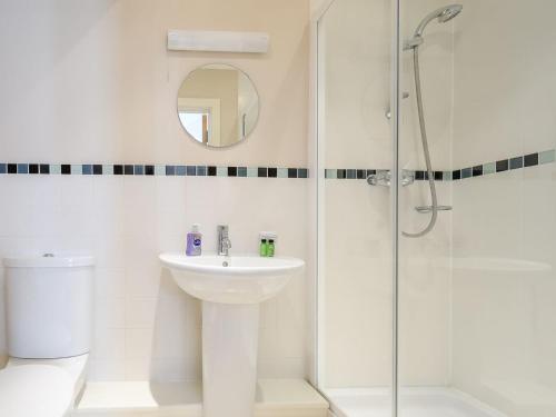 a white bathroom with a sink and a shower at Honey Cottage in Somerford Keynes