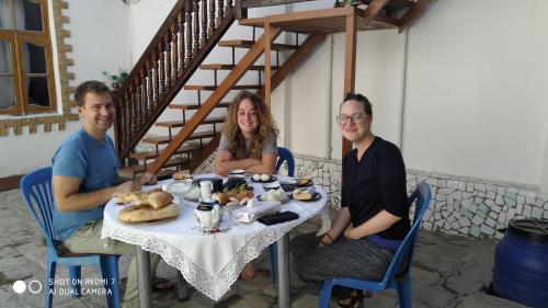 un grupo de tres personas sentadas en una mesa con comida en Ali Nur en Bukhara