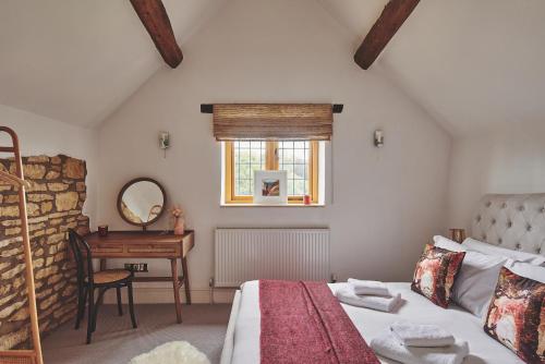 a bedroom with a bed and a table and a window at Squirrel Barn in Moreton in Marsh