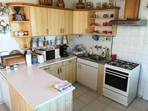 cocina con armarios de madera y horno de fogón blanco en Tóbiás Tanya Vendégház, en Hódmezővásárhely