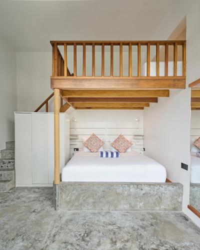 a bedroom with a white bed with a loft at Bliss Dhigurah in Dhigurah