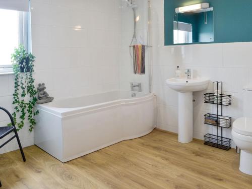 a white bathroom with a tub and a sink at Gin Case in Templand