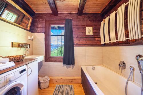 een badkamer met een bad en een wasmachine bij Bergchalet Schennaberg in Schenna