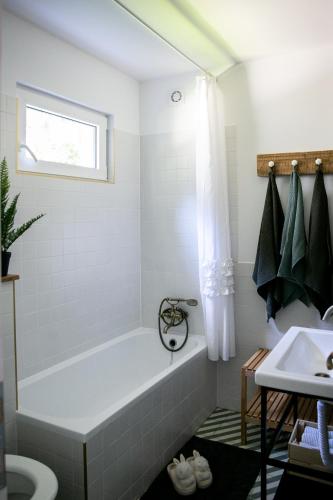 a white bathroom with a tub and a sink at Kikapcsol-LAK in Bogács