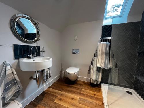 een badkamer met een wastafel, een toilet en een spiegel bij Secluded Island Retreat - in the heart of the Anchorage in West Mersea