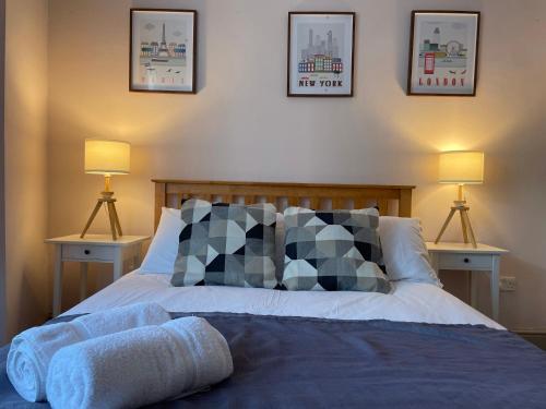 een slaapkamer met een bed met kussens en 2 lampen bij 43 Kimberly road apartment in Londen