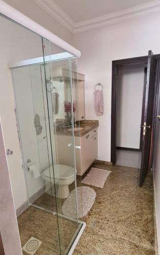 a bathroom with a glass shower and a toilet at Theora Quarto Amora in Blumenau