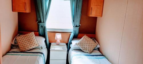 twee bedden in een kleine kamer met een raam bij Bayview Brixham in Brixham
