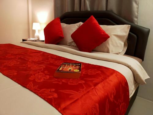 1 cama con almohadas rojas y blancas y control remoto. en Orchidilla Residence Phuket Mai Khao Beach - SHAPlus, en Mai Khao Beach