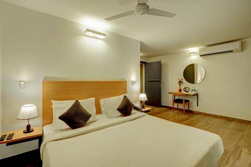 a bedroom with a large white bed and a table at Hotel Plaza Inn by Rio in Calangute