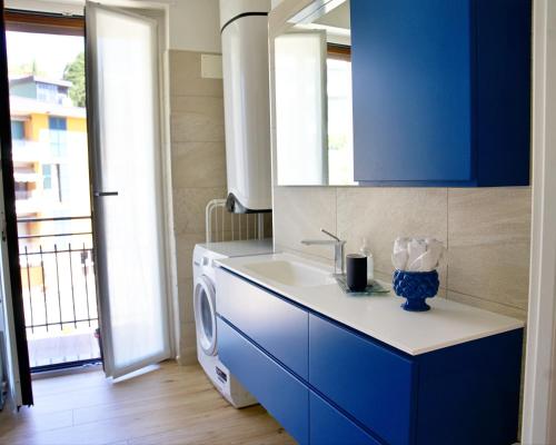 una cucina blu con lavandino e lavatrice di The Blue - lake / city view modern apt near villa Olmo a Como
