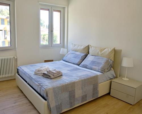 una camera da letto bianca con un letto e asciugamani di The Blue - lake / city view modern apt near villa Olmo a Como