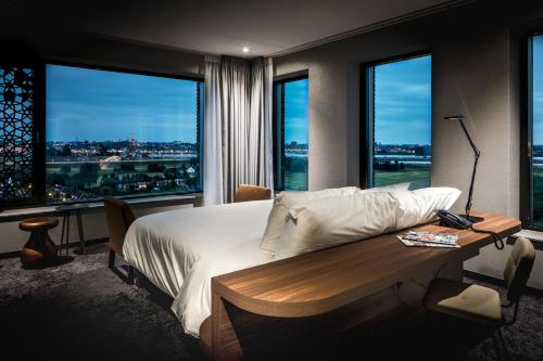 a bedroom with a bed and a table and windows at Van der Valk Hotel Nijmegen-Lent in Nijmegen