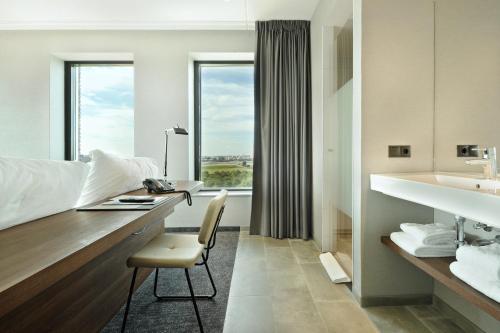 een badkamer met een bureau met een stoel en een wastafel bij Van der Valk Hotel Nijmegen-Lent in Nijmegen