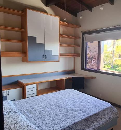 a bedroom with a bed and a desk and a window at Theora Quarto Amora in Blumenau