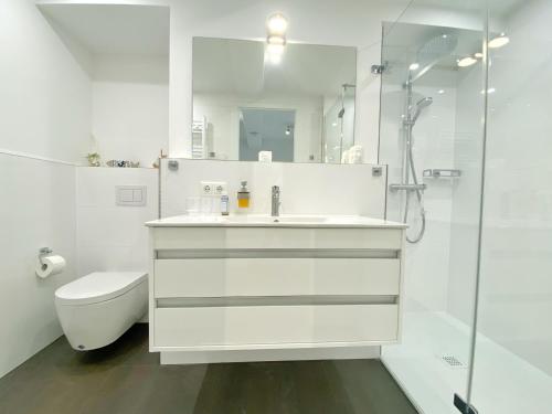 ein weißes Bad mit einem Waschbecken und einer Dusche in der Unterkunft Ferienwohnung "Jolle" in Binz