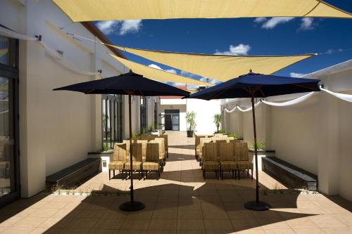 a patio with tables and chairs and umbrellas at Distinction Palmerston North Hotel & Conference Centre in Palmerston North
