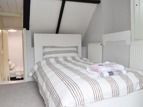 a bedroom with a white bed with striped sheets at Brook Cottage in Dawlish