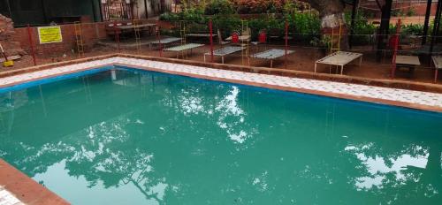 una piscina de agua azul y algunos bancos en Veg park view hotel matheran en Mātherān