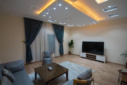 a living room with a couch and a flat screen tv at منازل بلقيس للشقق المخدومة in Hail