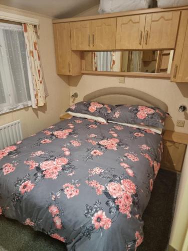 a bedroom with a bed with pink flowers on it at Meadow Lakes 56 in Chapel Saint Leonards