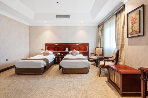 a hotel room with two beds and a desk at Chairmen Hotel in Doha