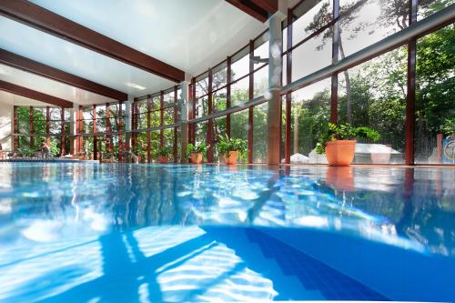 a swimming pool in a building with windows at Hotel Dom Zdrojowy Resort & SPA in Jastarnia