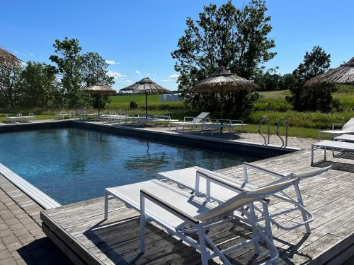 a swimming pool with chairs and umbrellas on a deck at STF Hostel Ihre Gård in Ire