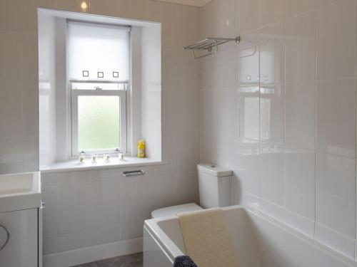 a bathroom with a tub and a toilet and a window at Charlotte Street in Ayr