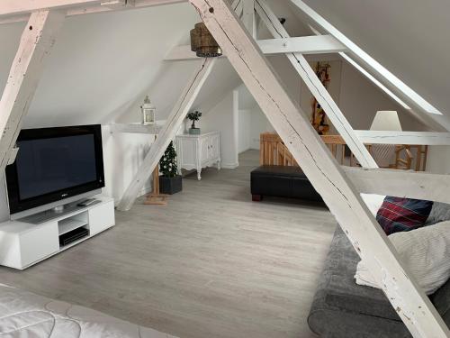 a living room with a tv and a staircase at Altes Gewölbe mit Sauna und Whirlpool im Außenbereich in Elsterheide