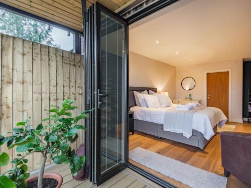 a bedroom with a bed and a sliding glass door at The Barn At Whitefields in Walcot