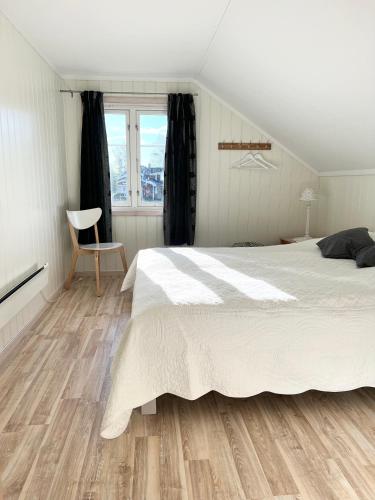 a bedroom with a white bed and wooden floors at Villa Granhede -sjöläge med badtunna, eldstad med mera in Torsby