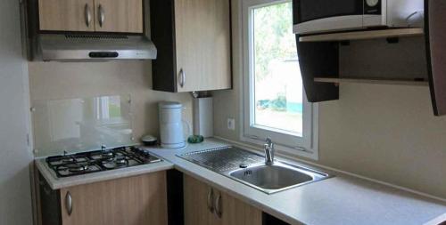 a small kitchen with a sink and a window at Camping le Moulin de David -Gaugeac Monpazier 24540 - Cabane -Mobil-home 3 et 2 chambres in Gaugeac
